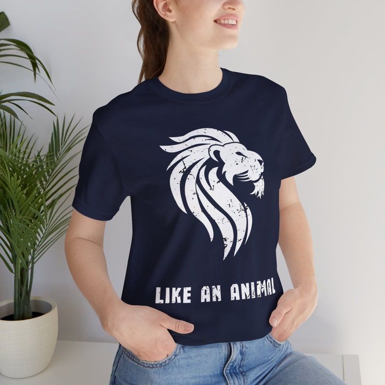K&ouml;nnte beinhalten: Ein marineblaues T-Shirt mit einem wei&szlig;en, abgenutzten L&ouml;wenmotiv und dem Text "LIKE AN ANIMAL" auf der Vorderseite.
