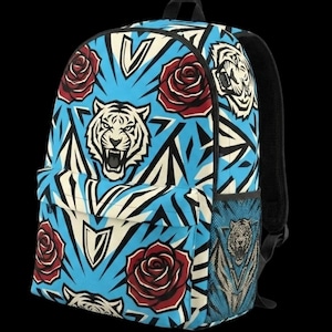 May include: A backpack featuring a repeating pattern of white tiger heads with open mouths, red roses, and black geometric shapes on a bright blue background. The bag includes a front zipped pocket, a top handle, and a side mesh pocket.