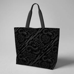 May include: A black tote bag featuring a repeating pattern of coiled snakes and blooming roses in shades of dark grey and black. The bag has two sturdy black shoulder straps and a rectangular shape with a flat base, showcasing a detailed graphic.