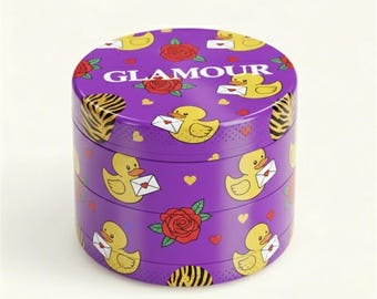 May include: A three-tiered purple container with a repeating pattern of yellow ducks holding envelopes, red roses, and hearts. The word "GLAMOUR" is printed on the top. The sides have a zebra print.