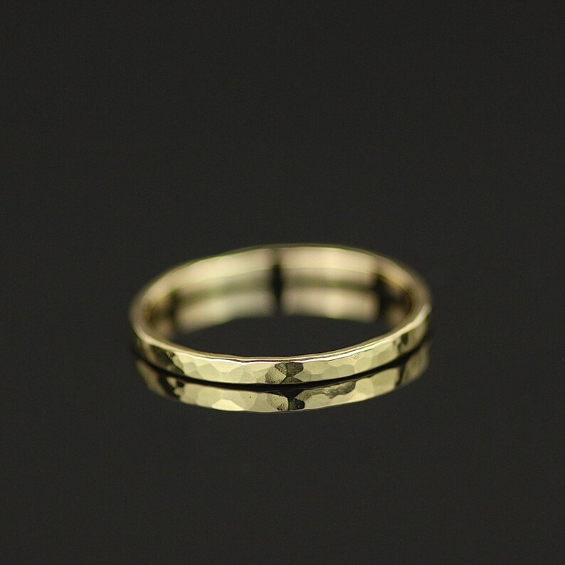 May include: A simple gold band ring with a hammered texture.