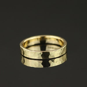 May include: A gold hammered wedding band. The band is smooth and has a slightly textured surface.
