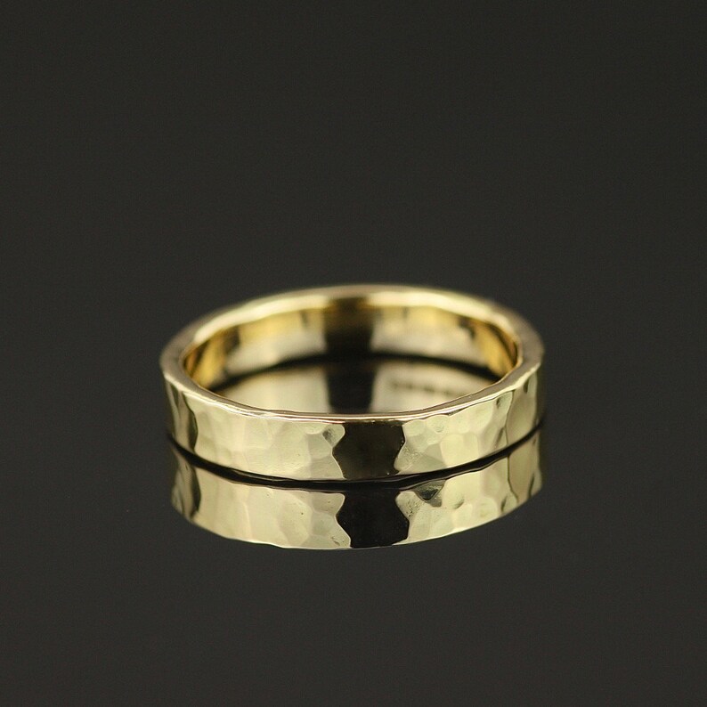 May include: A gold hammered wedding band. The band is smooth and has a slightly textured surface.