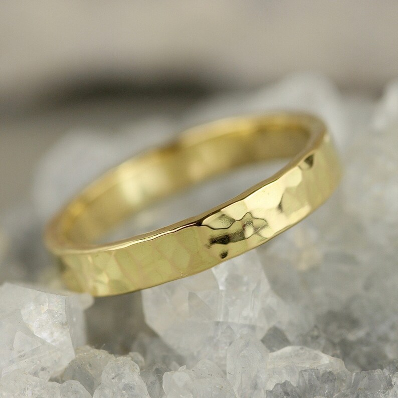 May include: A gold hammered band ring. The ring is made of a smooth, polished metal and has a textured surface.