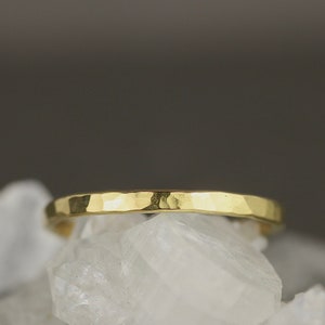 May include: A thin gold band ring with a hammered texture.