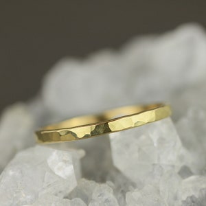 May include: A thin gold band ring with a hammered texture.
