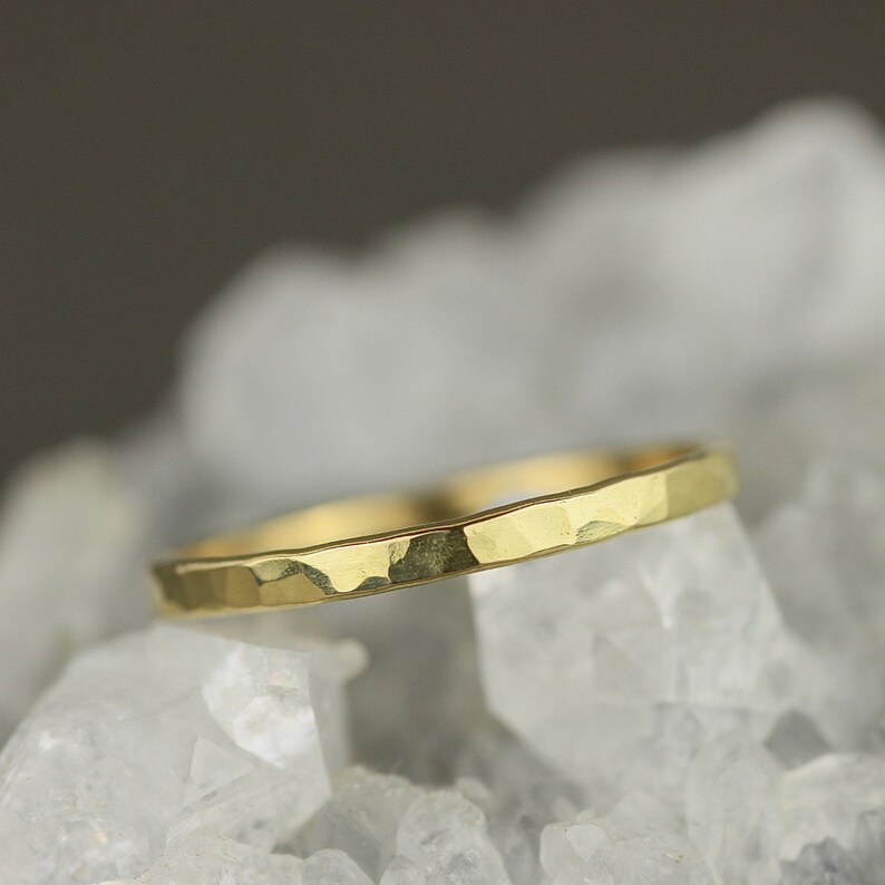May include: A thin gold band ring with a hammered texture.