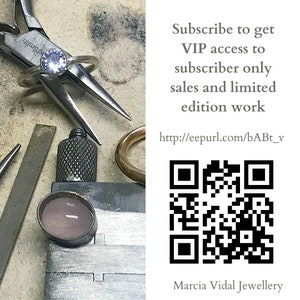 May include: A close-up of a silver ring with a light purple gemstone. The ring is being held by a pair of pliers on a workbench. The image also includes a QR code and text that reads "Subscribe to get VIP access to subscriber only sales and limited edition work http://eepurl.com/bABt_v Marcia Vidal Jewellery".