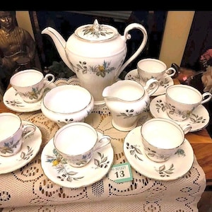May include: A vintage tea set with a floral pattern. The set includes a teapot, creamer, sugar bowl, and six teacups and saucers.
