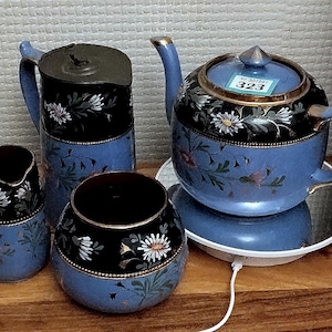 Puede incluir: Un juego de cuatro tazas de té y una tetera de color azul y blanco con flores. La tetera tiene un borde dorado y una etiqueta que dice "No. 301921 323".