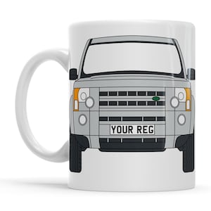 Peut inclure: Mug en céramique blanche avec un design de SUV gris. L'avant du véhicule est représenté avec des phares, une calandre et le texte "YOUR REG" sur la plaque d'immatriculation. La tasse a une anse blanche.