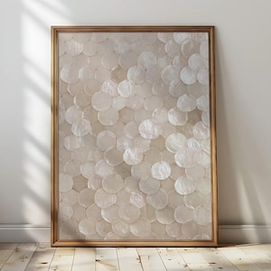 May include: A framed artwork featuring a pattern of overlapping, iridescent, circular shapes. The circles are primarily white and cream, with subtle variations in tone. The frame is a warm, light brown color. The artwork is displayed against a white wall.