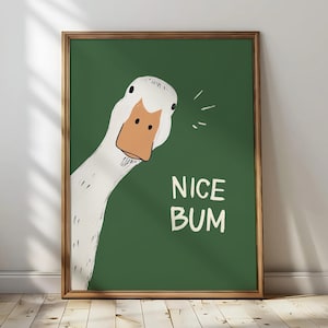 Puede incluir: Un cuadro enmarcado con una ilustración de un ganso de dibujos animados. El ganso tiene un cuerpo blanco y un pico naranja, sobre un fondo verde. El texto "NICE BUM" se muestra en blanco.