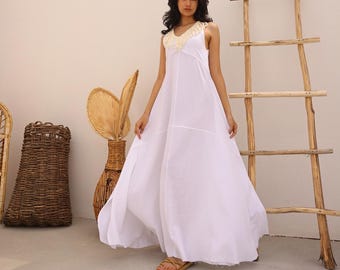 May include: A white maxi dress with a crocheted neckline and a flowy silhouette. The dress is sleeveless and has a relaxed fit.