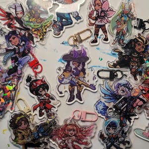 May include: A collection of acrylic charms featuring anime-style characters. Each charm has a unique design, with vibrant colors and intricate details. The charms are attached to keychains with various clasp styles, including lobster clasps and split rings.