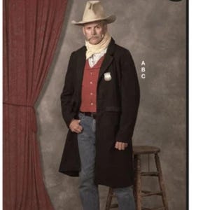 May include: McCall's Costumes pattern featuring a man in a cowboy costume. The man wears a black coat, red vest, blue jeans, and a cowboy hat. The background includes a red curtain and a wooden stool.
