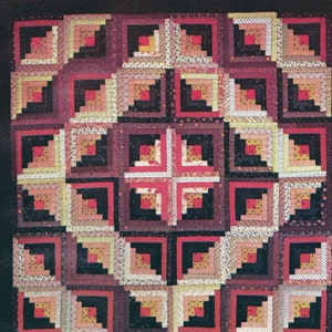 May include: A quilt with a log cabin pattern in shades of pink, red, brown, and black. The quilt is made of narrow strips of fabric sewn together to create a geometric design. The quilt is called "Barn Raising" and is a Pennsylvania Dutch crib quilt from around 1900.