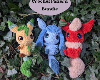 Puede incluir: Paquete de patrones de crochet con tres peluches amigurumi: un Eevee verde y amarillo, un Espeon azul y un Flareon rojo. Los peluches están sentados en un lecho de hojas verdes. El texto "Crochet Pattern Bundle" está escrito en un óvalo morado sobre los peluches.