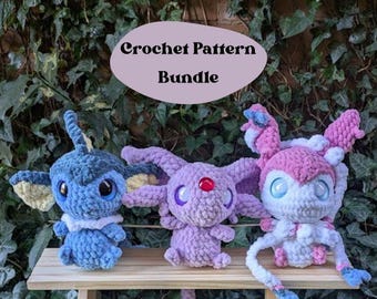 Op de afbeelding: Crochetpatroonbundel met drie amigurumi-knuffels: een blauwe Eevee, een paarse Espeon en een roze Umbreon. De knuffels zitten op een houten plank tegen een achtergrond van groene klimop.