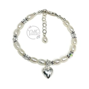 May include: A silver bracelet with white pearls, silver beads, and a silver heart charm. The bracelet has an adjustable clasp.