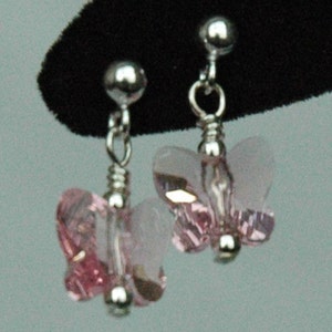 May include: A pair of silver butterfly earrings with pink crystal accents.