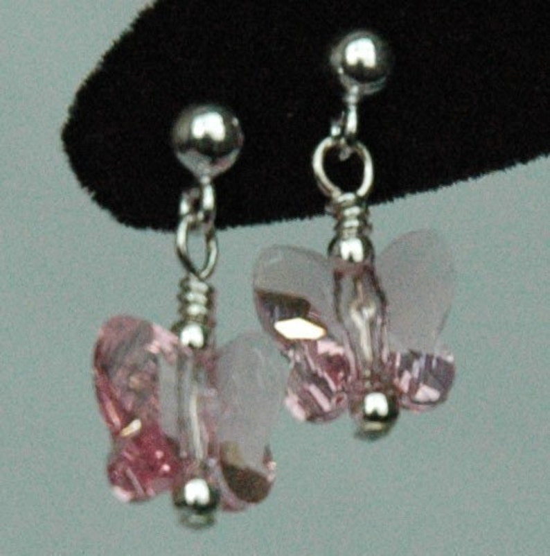 May include: A pair of silver butterfly earrings with pink crystal accents.