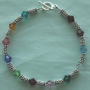 Peut inclure: Un bracelet en argent avec un fermoir à glissière et des perles de cristal arc-en-ciel.