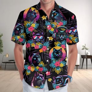 May include: A short-sleeved button-down shirt with a black background featuring a repeating pattern of black cats, some wearing headphones or sunglasses, interspersed with colorful tropical flowers, green leaves, and circular sunset motifs.