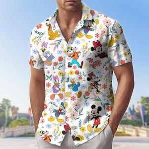 May include: White short-sleeved button-down shirt featuring a colorful pattern of Disney cartoon characters and flowers. The shirt includes images of Mickey Mouse, Minnie Mouse, Donald Duck, Daisy Duck, Goofy, and Pluto. The shirt is worn by a person.