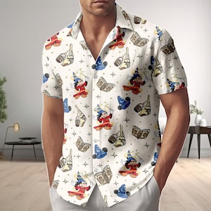 Könnte beinhalten: Weißes Button-Down-Hemd mit einem sich wiederholenden Muster eines Zeichentrickcharakters in einem Zauberer-Outfit, Zauberbüchern, Zauberhüten und Zauberstäben. Das Hemd hat kurze Ärmel und einen klassischen Kragen. Das Hemd wird von einer Person getragen.