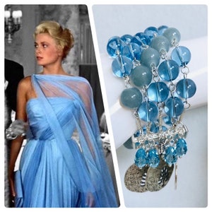 May include: A bracelet with blue beads and silver accents. The bracelet features multiple strands of round, translucent blue beads and opaque blue beads. Silver chains connect the strands, with dangling blue teardrop beads and silver leaf charms.