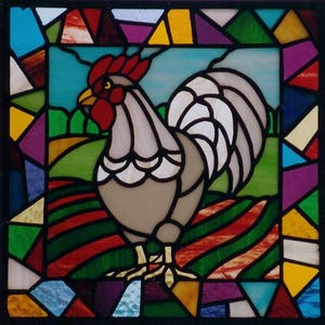 May include: A stained glass window depicting a rooster in a field. The rooster is gray with a white tail and red comb. The field is green with red and green stripes. The window is surrounded by a border of colorful glass.
