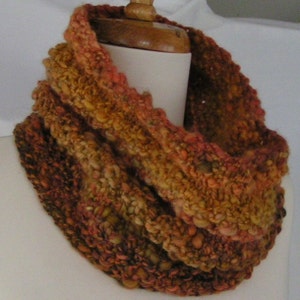 May include: A brown, orange and red knitted infinity scarf with a textured, chunky knit pattern.