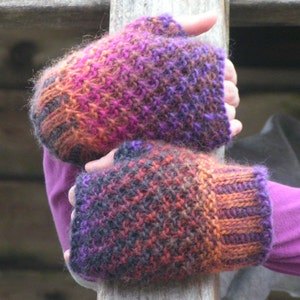 May include: A pair of fingerless gloves in a multi-colored knit pattern with shades of purple, pink, orange, and black.