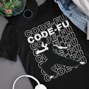 Könnte beinhalten: Schwarzes T-Shirt mit einer weißen Silhouette einer Person, die eine Kampfkunstpose einnimmt. Der Text "CODE-FU" wird in weißen Buchstaben auf der Vorderseite des Shirts wiederholt.