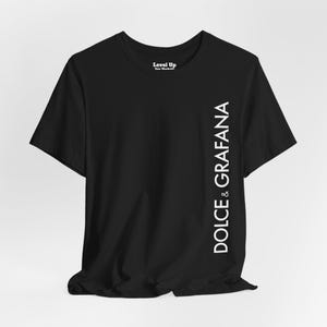Może przedstawiać: Czarny T-shirt z białym tekstem, który głosi "& DOLCE & GRAFANA" pionowo po prawej stronie koszulki.