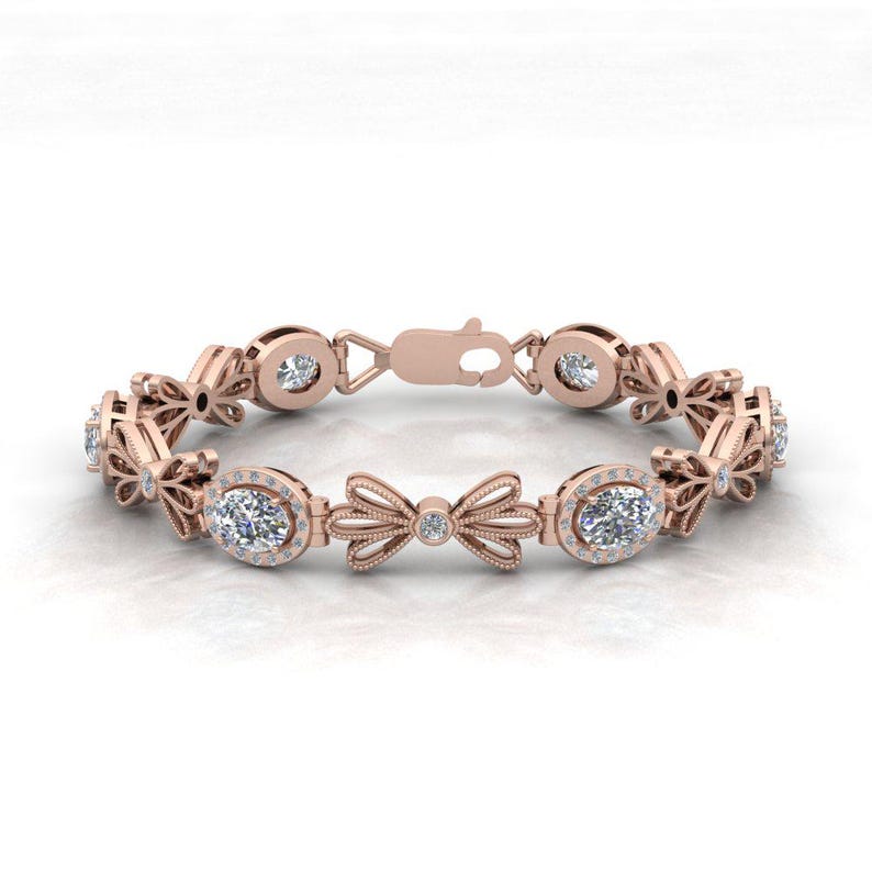 May include: A rose gold bracelet with oval-shaped diamonds set in a halo setting. The bracelet features a delicate bow design with smaller diamonds.