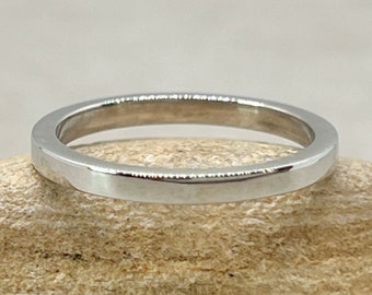 May include: A simple, silver wedding band with a flat, polished surface.