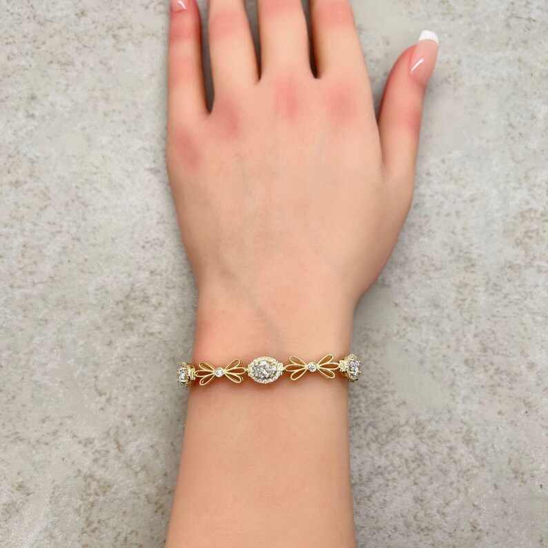 May include: A gold bracelet with a delicate design featuring small, clear stones and bow-shaped accents.