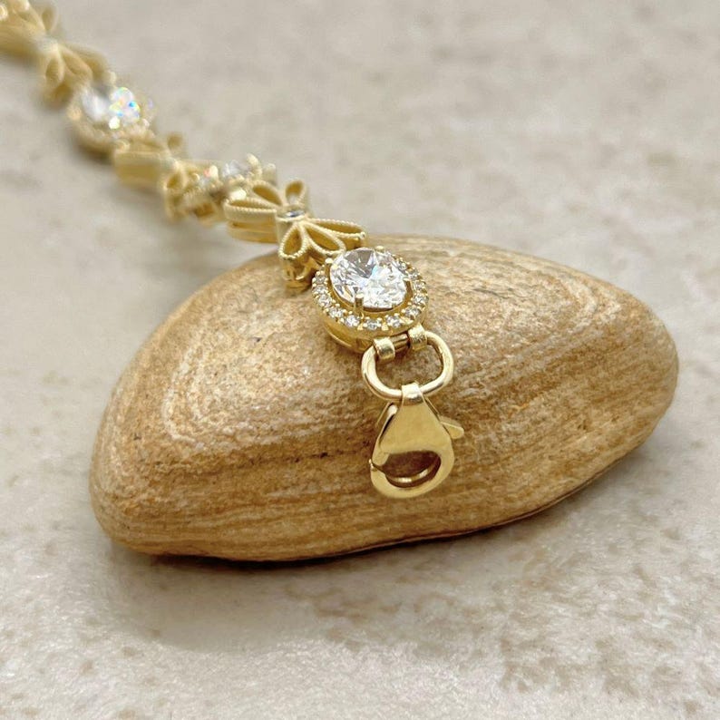May include: A gold bracelet with a delicate floral design and clear cubic zirconia stones. The bracelet has a lobster claw clasp.