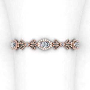 May include: A delicate rose gold bracelet with a central oval-shaped diamond surrounded by smaller diamonds. The bracelet features a repeating pattern of bows on either side of the central diamond.