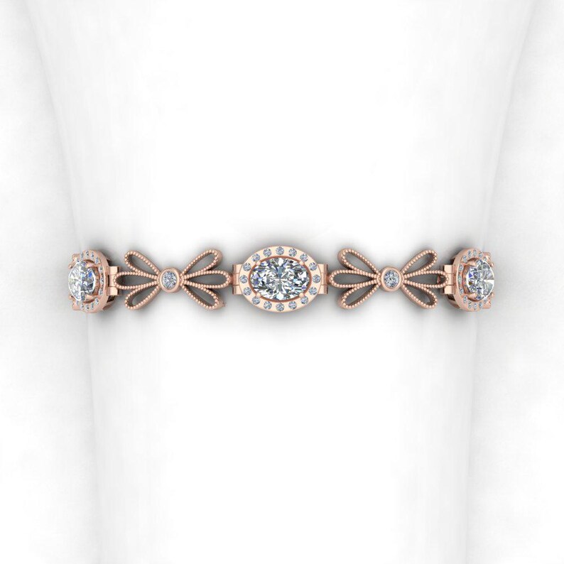 May include: A delicate rose gold bracelet with a central oval-shaped diamond surrounded by smaller diamonds. The bracelet features a repeating pattern of bows on either side of the central diamond.