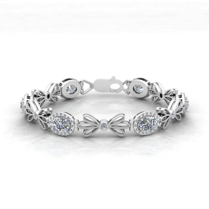May include: A silver bracelet with a delicate bow design and oval-shaped gemstones. The bracelet is adorned with small, sparkling diamonds.