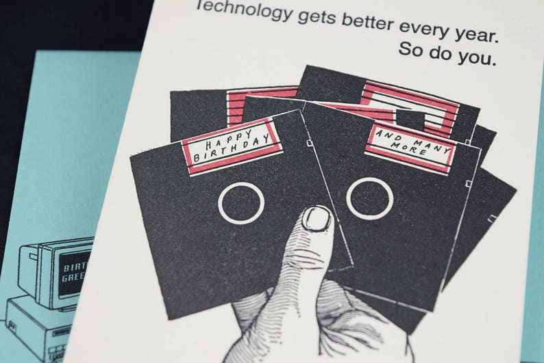 May include: A birthday card with a black and white illustration of floppy disks. The card has the text "Happy Birthday" and "And Many More" on the floppy disks.