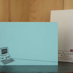 May include: A light blue card with a black and white illustration of a computer with the text "Birthday Greetings" on the screen. The card has a white border and the text "addallpress.com" in the bottom right corner.