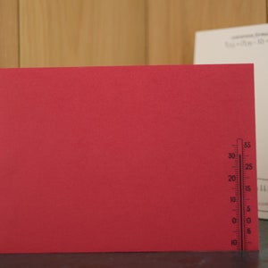 May include: A red card with a black thermometer printed on the right side. The thermometer has markings from -10 to 35 degrees.