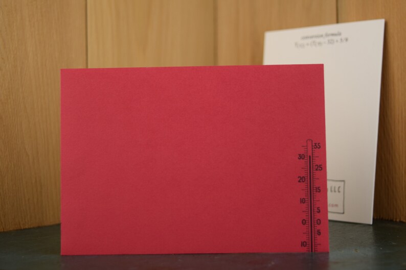 May include: A red card with a black thermometer printed on the right side. The thermometer has markings from -10 to 35 degrees.