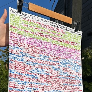 Può includere: Un lungo foglio di carta con testo manoscritto multicolore, tenuto da un appendiabiti in legno. Il testo è una sceneggiatura di Monty Python's Flying Circus, intitolata "Argument Clinic". La carta è tenuta all'aperto.