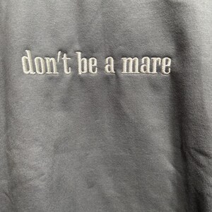 Puede incluir: Una sudadera gris con el texto "don't be a mare" bordado en blanco.