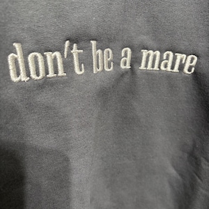 Puede incluir: Una sudadera gris oscuro con el texto "don't be a mare" bordado en blanco.